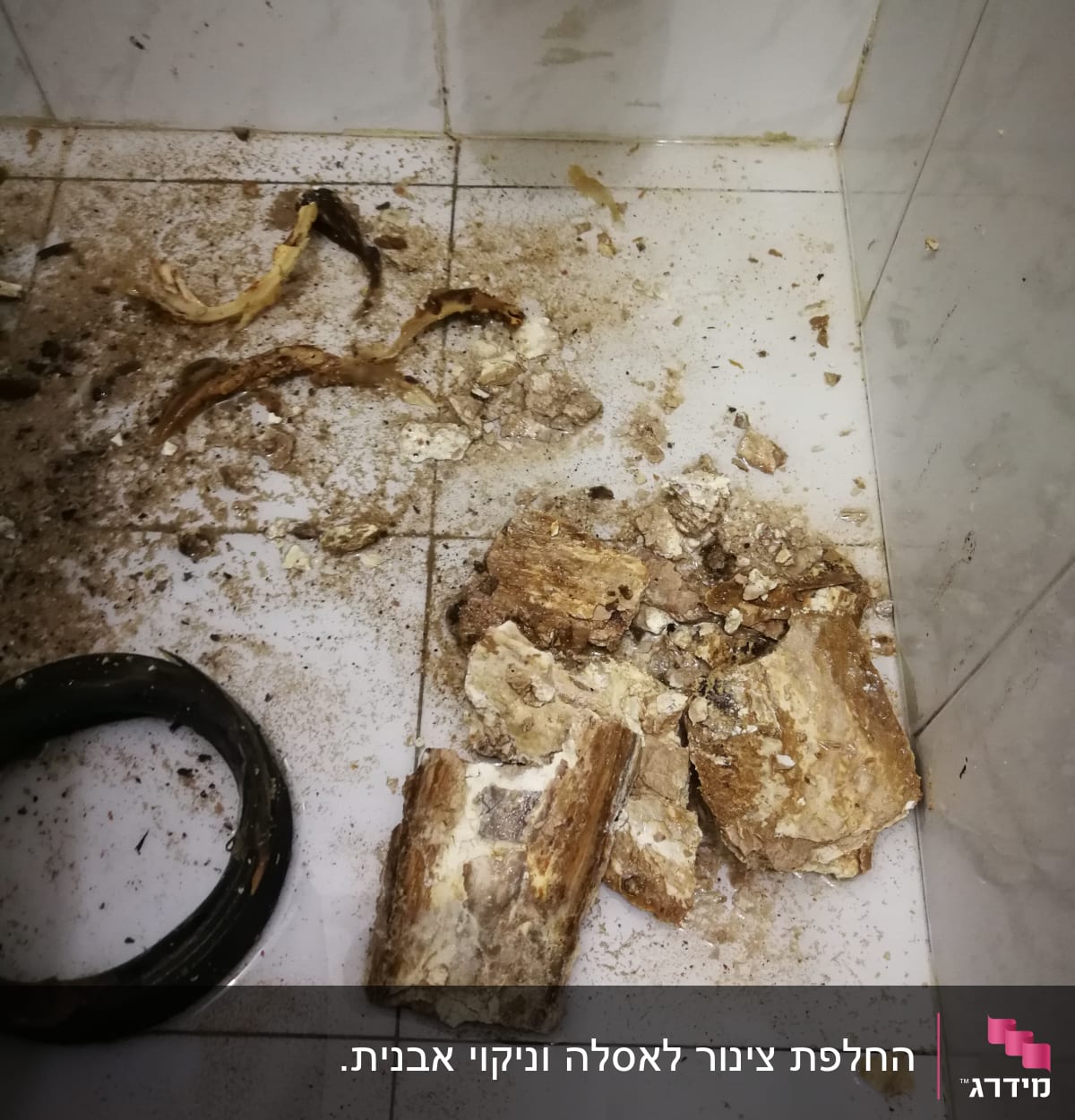 חלקי צינור שבור ופסולת על רצפת חדר אמבטיה
